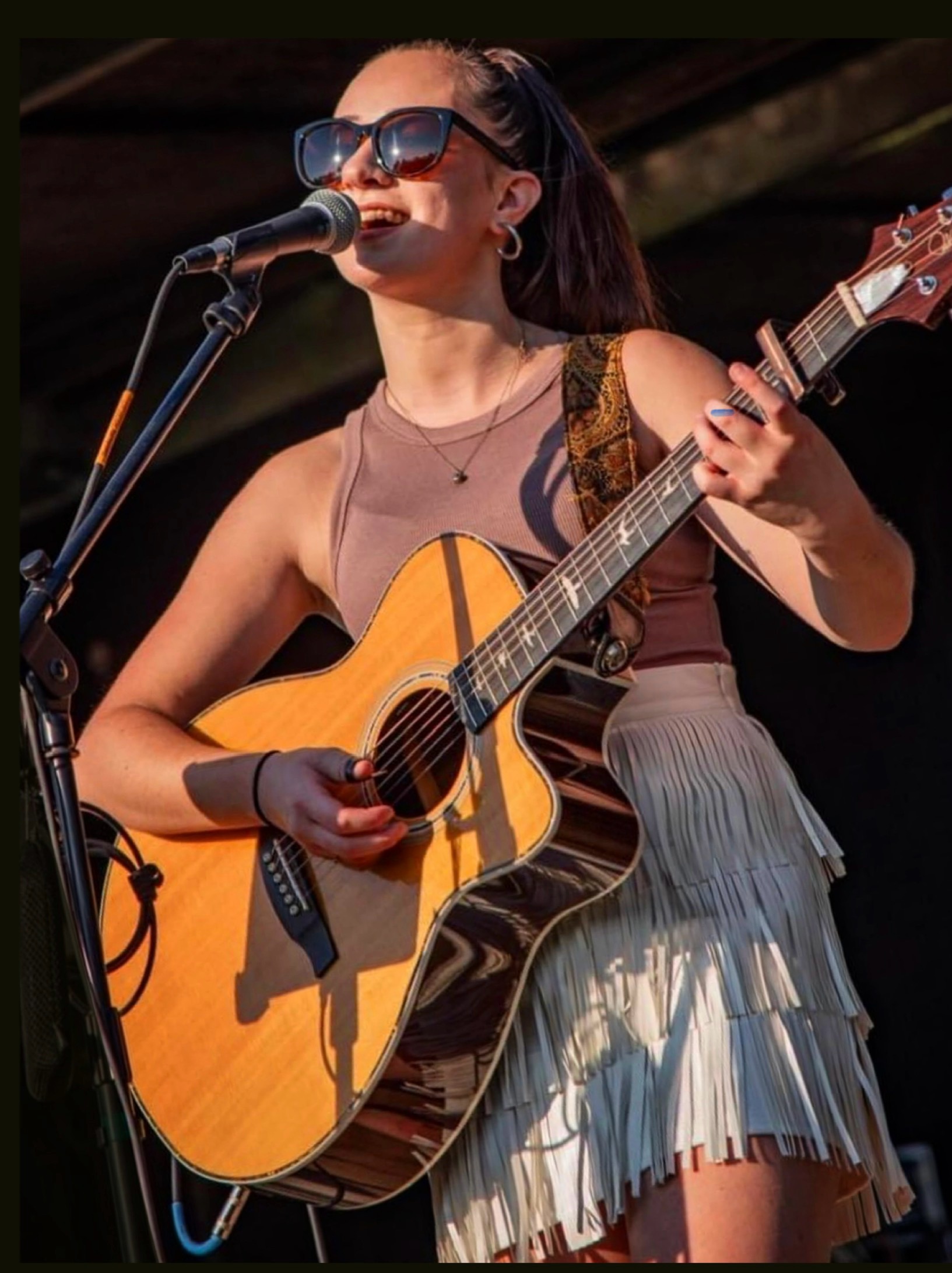Girl singing into a microphone play the guitar